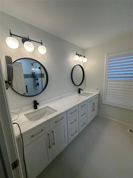 Double vanity round black mirrors gold hardware completed by NG Construction & Improvements